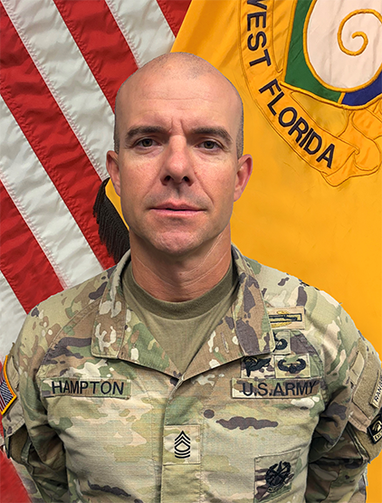 Houston Hampton indoor headshot in military uniform attire with the United States flag and University of Florida military flag in the background.