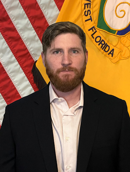 Landon Townsend indoor headshot in professional attire with the United States flag and University of Florida military flag in the background.