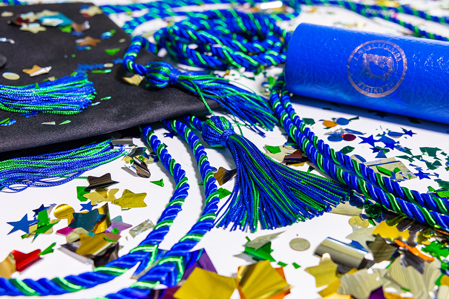 Graduation regalia surrounded by confetti.