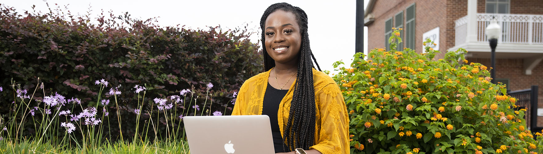 A UWF student smiles while using a laptop in downtown Pensacola.