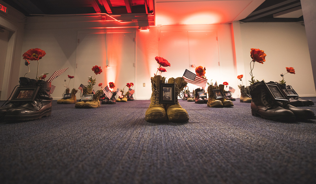 The 2022 Memorial Day Observance display showcases roses placed in military boots, along with photos in memory of service members.