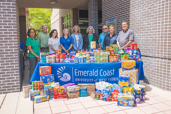 Group of people standing behind a table displaying various food cans and boxes.