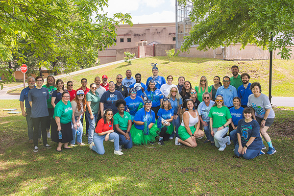 A large group of people standing or kneeling on grass for an outdoors group photo.