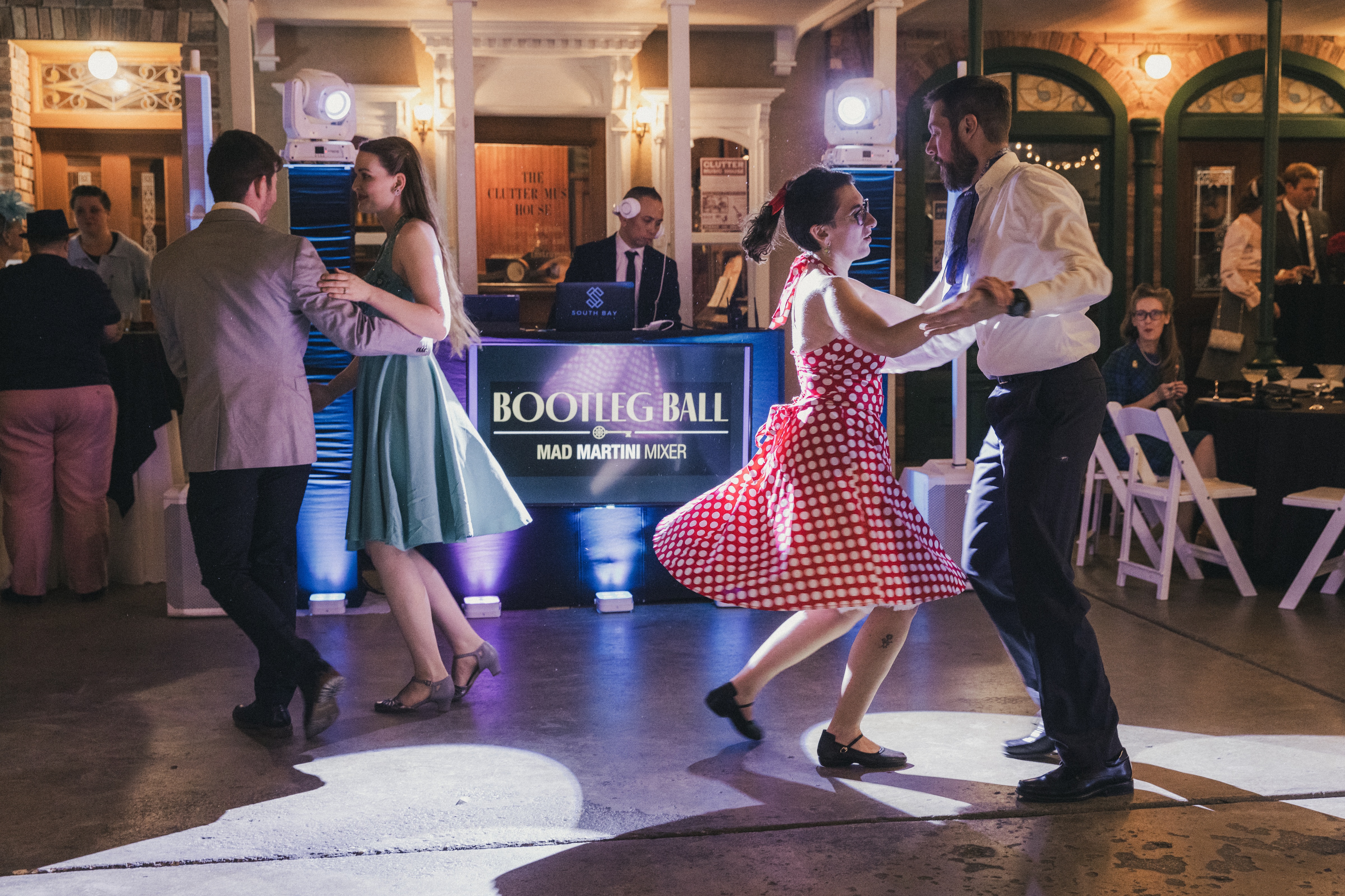 Four people in 1950's attire dancing at the Bootleg Ball Mad Martini Mixer with people in the background watching.