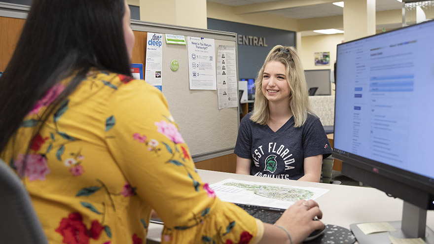 A UWF student smiles at an advisor while meeting in Argo Central.  