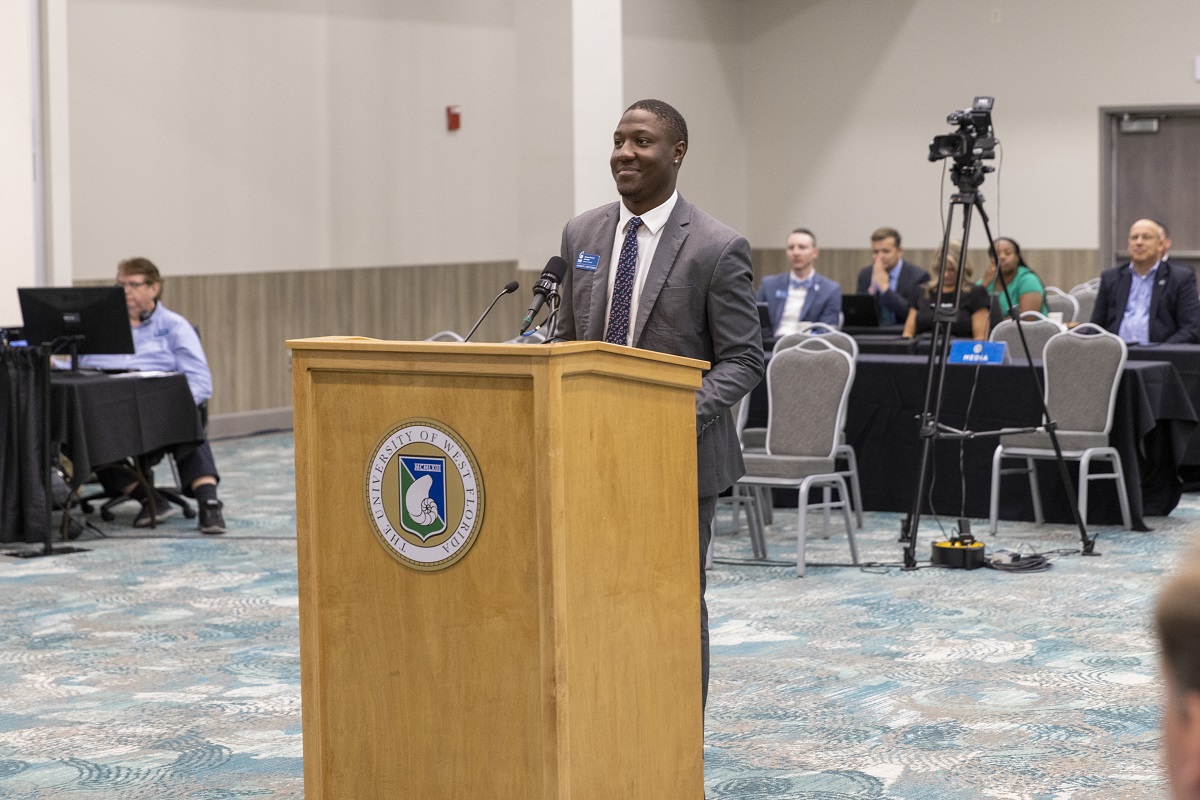 A student at a podium addressing the Board of Trustees