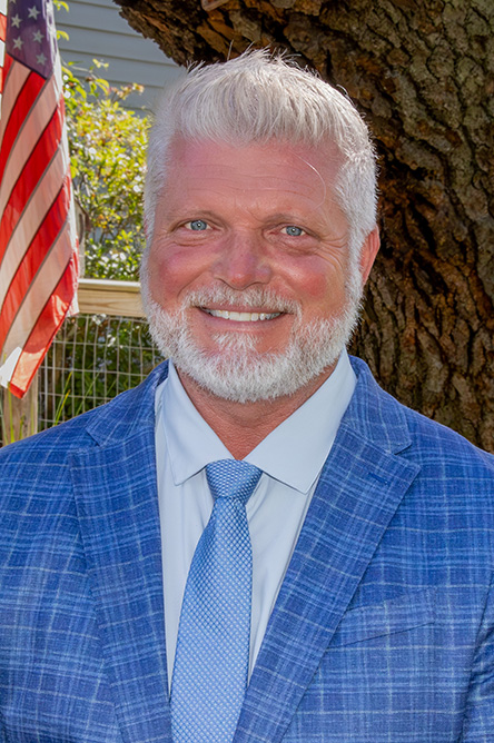 Chris Roney outdoor headshot in suit and tie attire.
