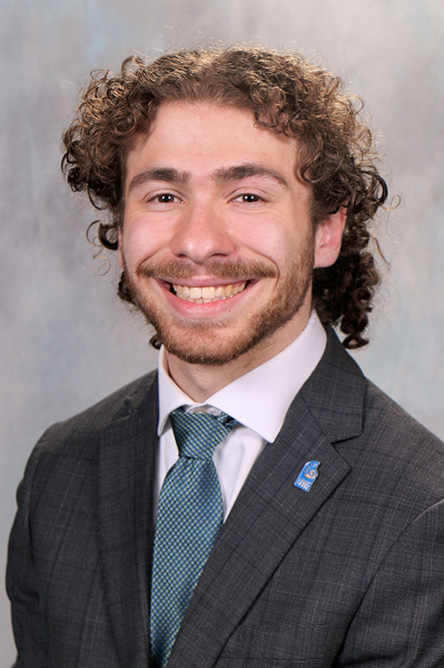 Eli Schatz indoor headshot in suit and tie attire.