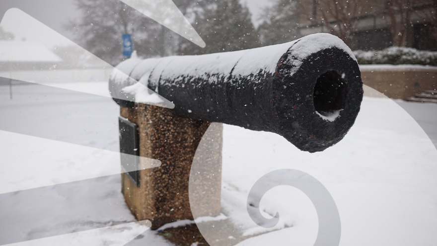 Cannon monument and the surrounding ground area covered in snow during a snowstorm.