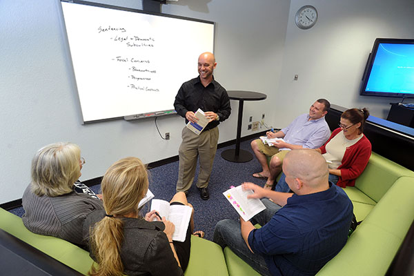 students seated in a semi-circle around a criminal justice professor giving a lecture