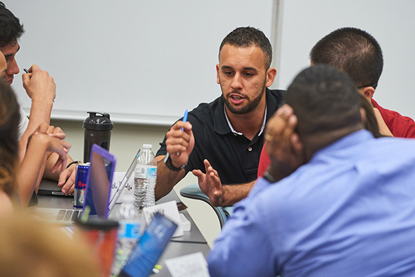 business students debating in a group at a desk