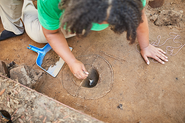 anthropology graduate student excavating a dig site in the field