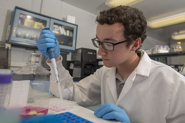 biomedical student filling test tubes in a lab