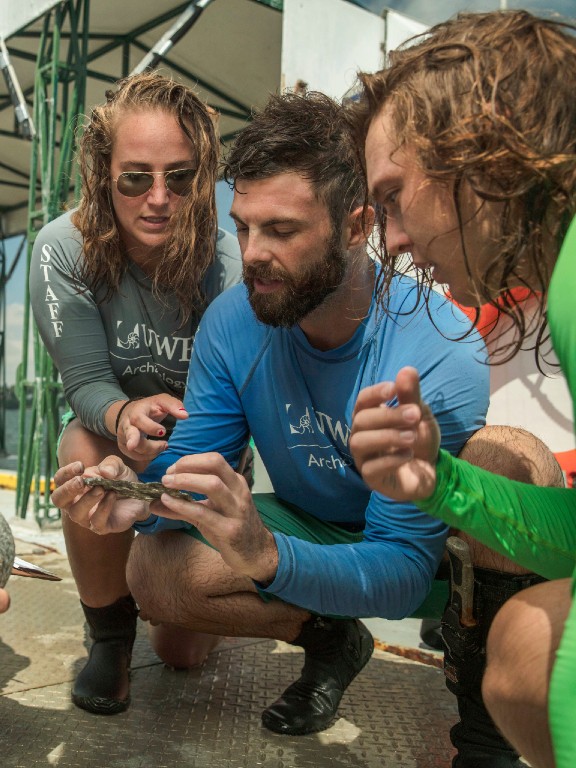 Historic preservation students and faculty examining an artifact in the field.