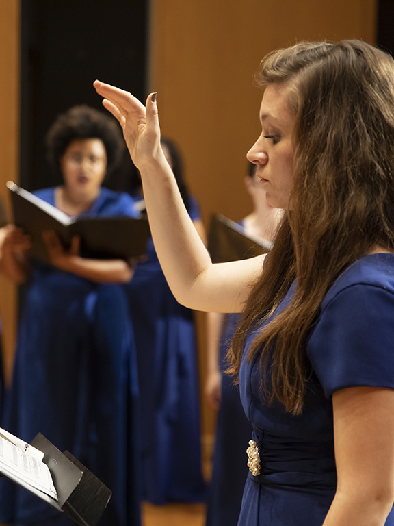 conductor leading a choir in the background