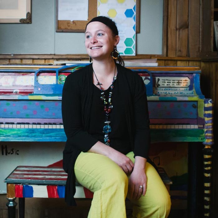 Dr. Izbicki sitting in front of a brightly painted piano
