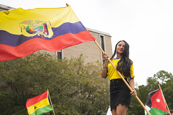 A student carrying a flag pole with the country flag of Ecuador.