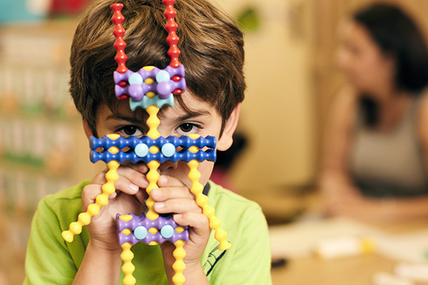 child looking at the camera through a toy figure