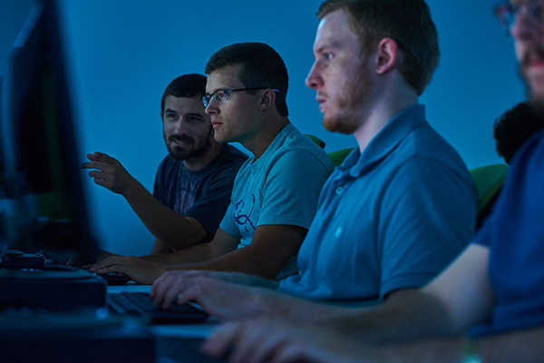 three computer engineering students in a row working in a computer lab