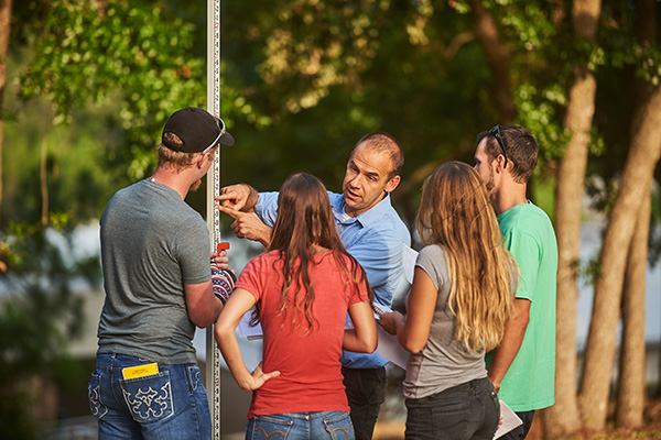 four students circled around an instructor at a construction site
