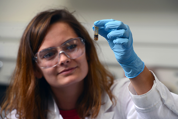environmental science student looking at a water sample in a test tube