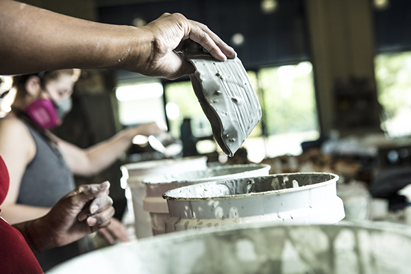 hand holding a ceramic dish over a paint bucket