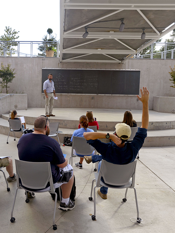 mathematics students studying on a blackboard outside of building 4