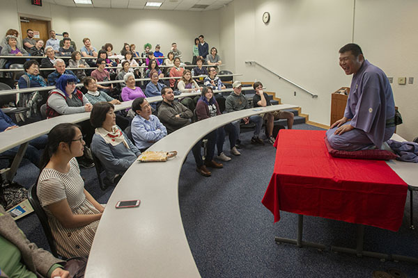 international studies class listening to a guest speaker who is sitting on a table