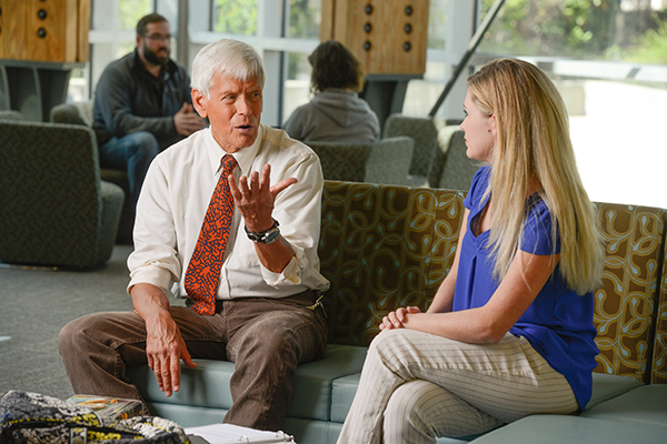 Marketing professor conversing with a student in the Building 76A atrium on the UWF Pensacola campus.