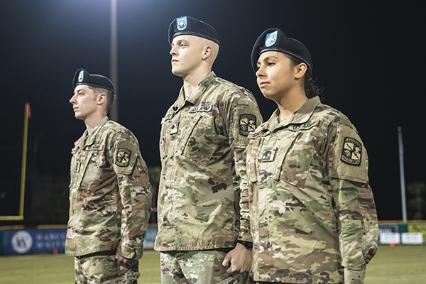 three students in military uniform on the uwf baseball field
