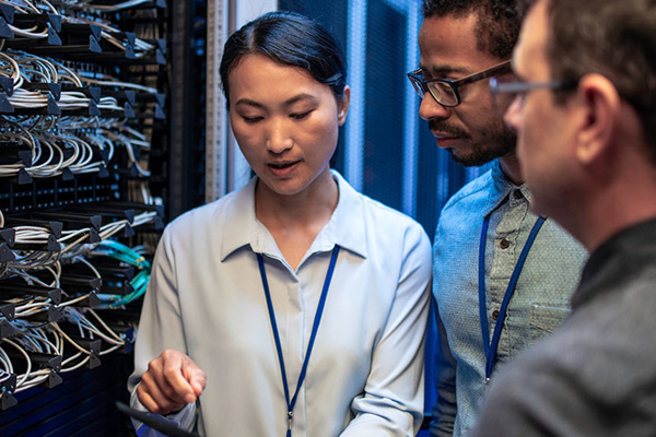 three IT workers in a server room
