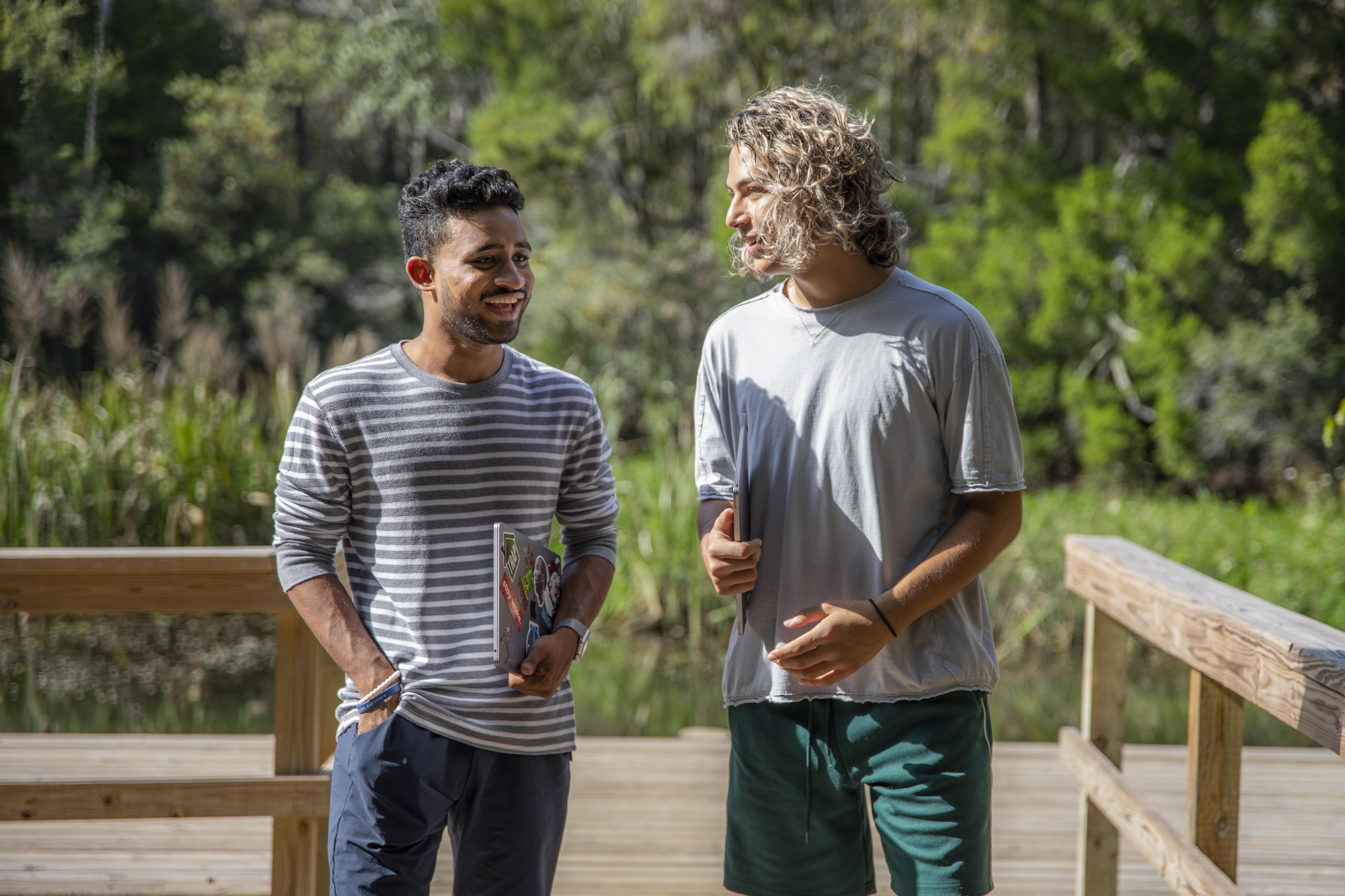 Two online students with laptops walking outside