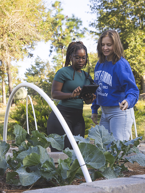 Student and instructor in garden working on GIS project