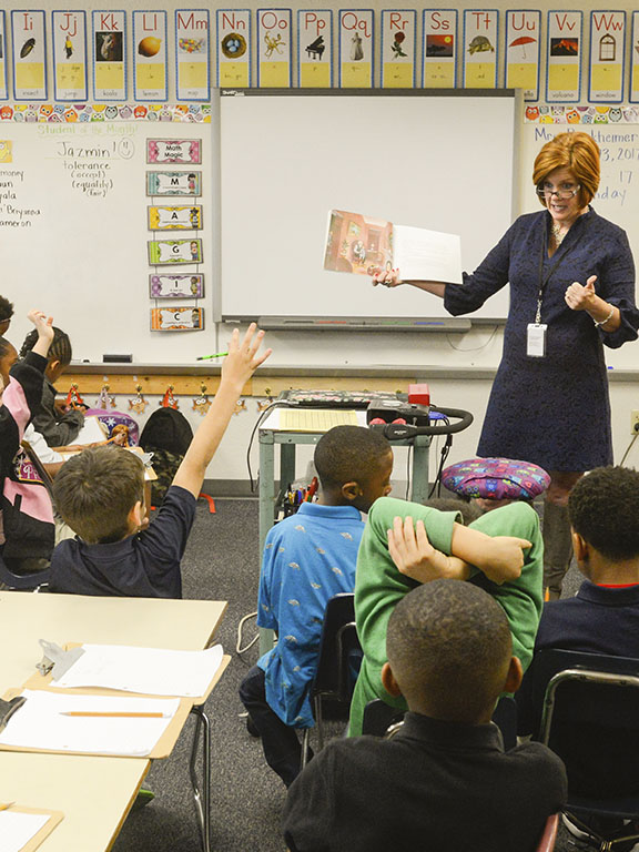 Teacher reading a story book to a classroom of young students.