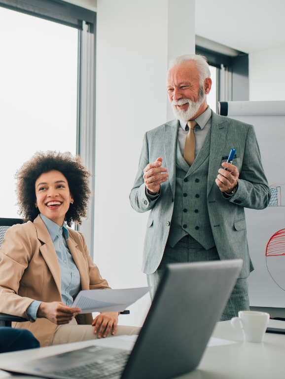 Two behavior analysts laughing during a meeting at a table.
