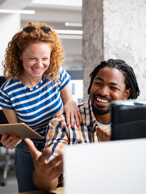 Two coworkers looking at computer screen in an office setting.