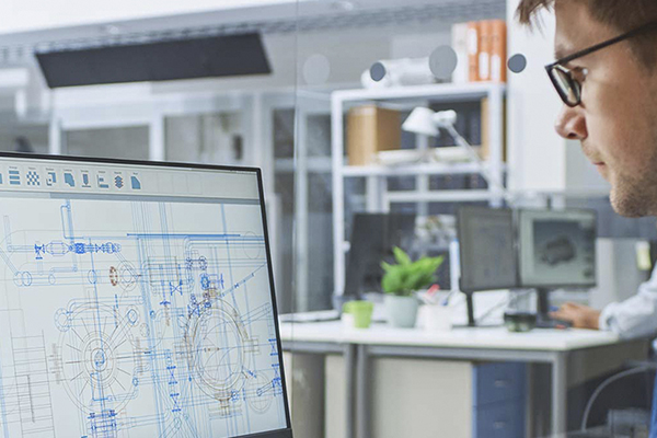 Engineering professional using a 3D modeling program on a computer in an office setting.