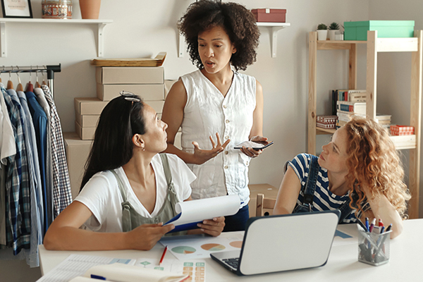 Three entrepreneur professionals conversing with two sitting at a table.