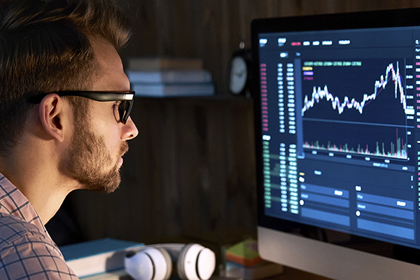 Business trader analyst looking at computer monitor, investor broker analyzing indexes, financial chart trading online investment data.