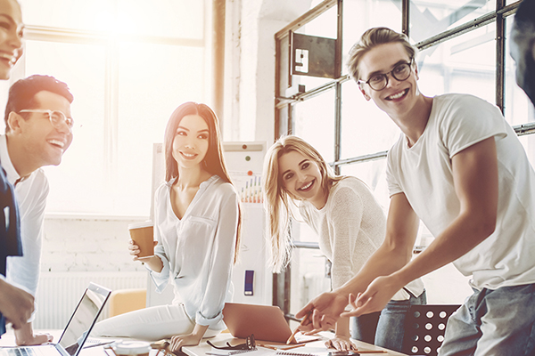 Group of people standing around a table working together on a project.
