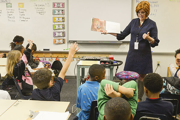 Teacher reading a story book to a classroom of young students.