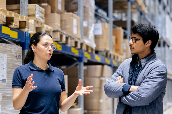 Two logistics experts conversing in a warehouse.