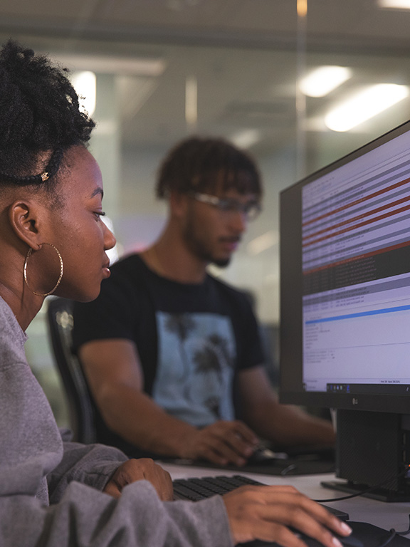 Two cybersecurity students working at computers