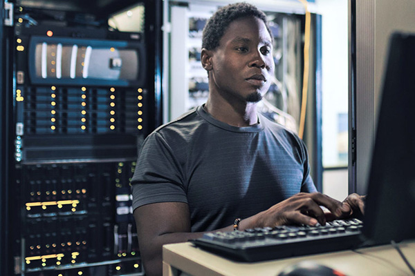 cybersecurity student typing on a terminal in a server room