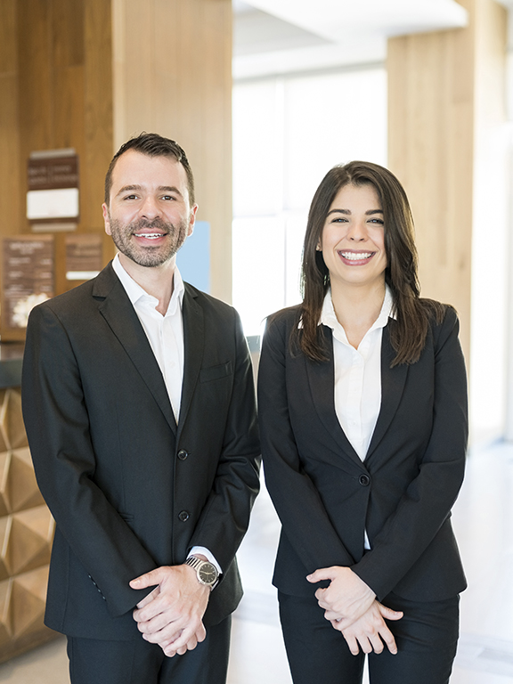 managers smiling while making eye contact against reception desk in hotel