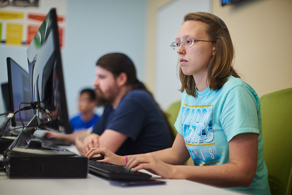 three software design students practicing programming in a computer lab
