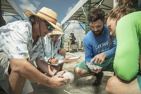 historic preservation students and faculty examining an artifact in the field