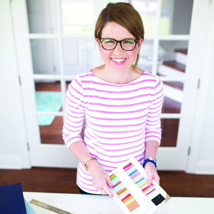 Emily Ley holding a piece of paper with small fabric square samples in various colors.