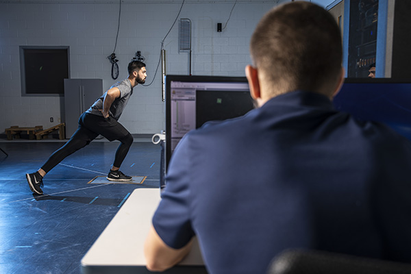student using a computer to analyze the effects of calisthenics on another student