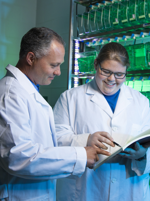 a professor and a student review lab results in a notebook
